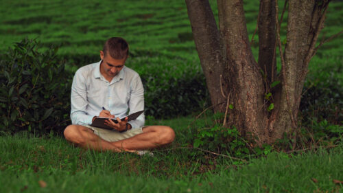 Young man sitting under tree engaging in deep work to become a better, more successful fundraiser.