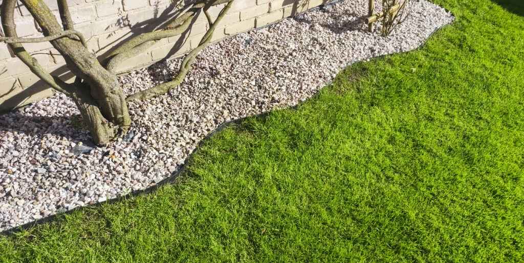 Lush green lawn with an edging of small garden stones