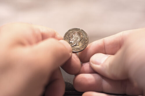 Close up capture of an Caucasian man hands holding and old greek new years cake coin showing king face